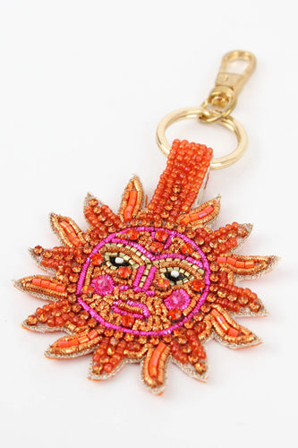 A keyring with a face on it handmade from beads sewn onto a faux suede back. Brightly coloured in orange, pink, gold