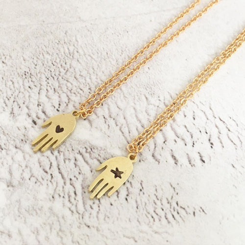 A small (1 cm) brass hand with either a star or heart carved out of it. Each is different as each is individually handmade. The pendants are presented on a gold plated trace chain