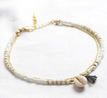 Load image into Gallery viewer, ankle chain of white beads and gold chain with a shell and tassel