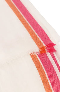 A lightweight cotton scarf which is very soft to the touch and has a delicate drape. In a cream colourway it features a bright pink and an orange herringbone stripe to the edge lengthways. With subtle fringing to each end.
