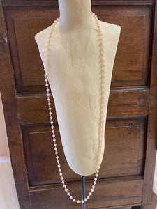 Soft pink iridescent beads attached to gold metal make this a beautiful long necklace with a clasp fastening.