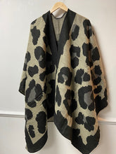 Load image into Gallery viewer, This ladies cape is supersoft and luxuriously warm to the touch. Like an oversized scarf, this cape simply drapes over your shoulders to keep you effortlessly warm and stylish. Wear like a cardigan or a coat over any outfit. In a black large oversized leopard print design, with black blanket stitching to all edges. One size. 