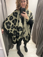 Load image into Gallery viewer, This ladies cape is supersoft and luxuriously warm to the touch. Like an oversized scarf, this cape simply drapes over your shoulders to keep you effortlessly warm and stylish. Wear like a cardigan or a coat over any outfit. In a black large oversized leopard print design, with black blanket stitching to all edges. One size.