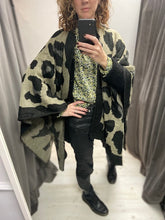 Load image into Gallery viewer, This ladies cape is supersoft and luxuriously warm to the touch. Like an oversized scarf, this cape simply drapes over your shoulders to keep you effortlessly warm and stylish. Wear like a cardigan or a coat over any outfit. In a black large oversized leopard print design, with black blanket stitching to all edges. One size.