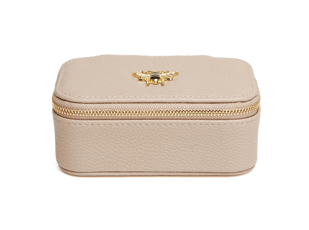 Stone coloured faux leather jewellery box with a gold bee detail on the top and a gold zip. Inside is ring storage, an open storage section and a mirror