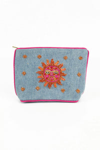 A simple rectangular purse with a brightly coloured bead sun face in orange, pink and gold