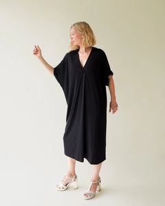 Black straight cut drape fabric dress with a v neck and sleeves that cover tops of arms