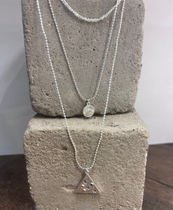 triple layered silver plated necklace with a triangular pendant with moon and stars and a circular one with the evil eye within sun rays