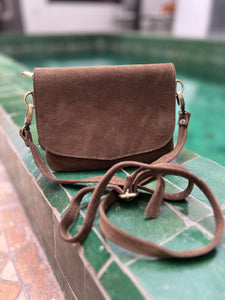 Golden brown suede mini handbag with a long adjustable strap and a wrist strap.