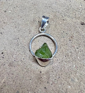 Green peridot crystal in a circular sterling silver setting