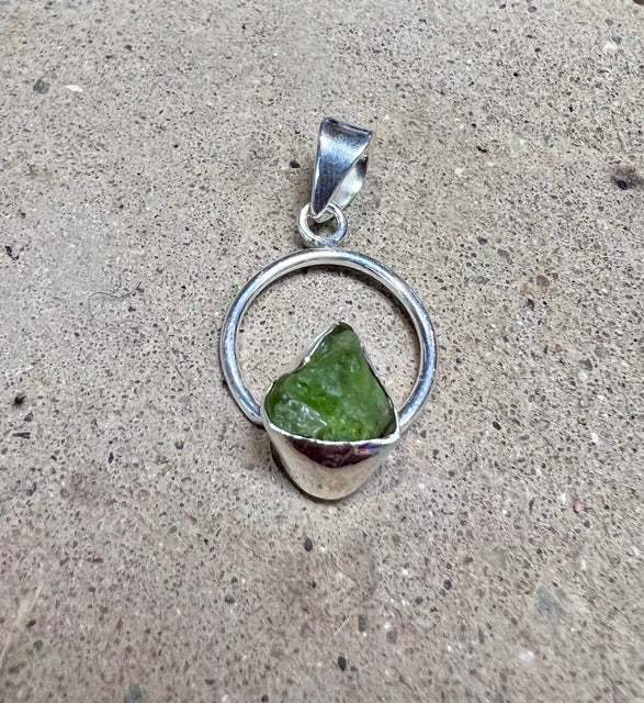 Green peridot crystal in a circular sterling silver setting