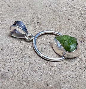 Green peridot crystal in a circular sterling silver setting