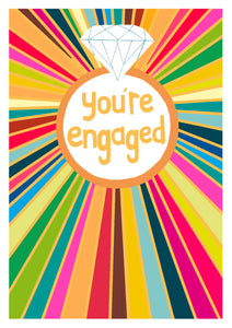 Engagement card with silver cut diamond and a rainbow of colours extending outwards from it with the words "you are engaged" in goldre 