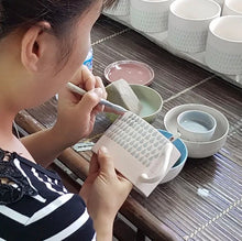 Load image into Gallery viewer, Image of the Vietnamese mugs being handpainted