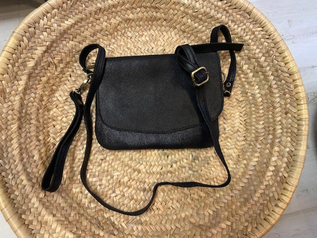 A handmade handbag from Morocco in black metallic leather. With a detachable wrist strap and a detachable longer length adjustable strap so it can also be worn as a crossbody bag. Flap front with zip main compartment. 