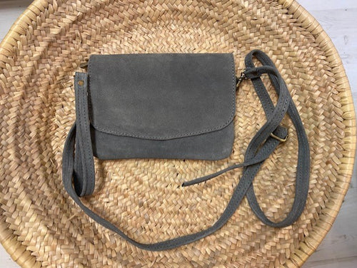A grey suede handbag which is handmade in Morocco. With a detachable wrist strap so it can be worn as a clutch bag, and a detachable adjustable strap so it can be worn across the body. 