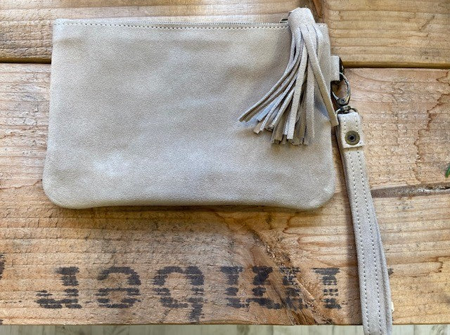 A clutch bag made in Morocco in genuine suede in a neutral colour. With an oversized tassel to the zip puller and a detachable wrist strap. 