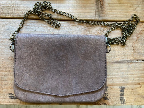 A rose gold metallic leather handbag, handmade in Morocco. With a detachable bronze chain strap, it has a flap closure and a zip fastening to the main compartment.