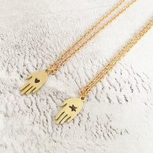Load image into Gallery viewer, A small (1 cm) brass hand with either a star or heart carved out of it. Each is different as each is individually handmade. The pendants are presented on a gold plated trace chain