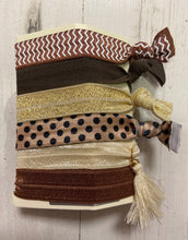 Load image into Gallery viewer, This set of hair ties features 6 different earth tone bobbles. The set includes a glittery gold hair tie, a chevron print, a spot print and 3 plain colours (brown, rust and cream). Perfect for keeping your hair tied up or even worn on your wrist as an accessory. 