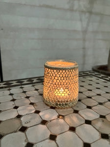 A small lantern made from recycled glass and woven rafia 