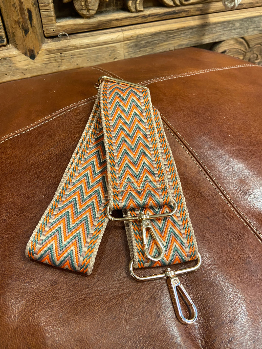 In orange and beige and neutral tones, this chevron design is a timeless classic. Fully adjustable in length, it features gold coloured hardware, and clasps to easily attach to your handbag. 