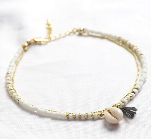 ankle chain of white beads and gold chain with a shell and tassel