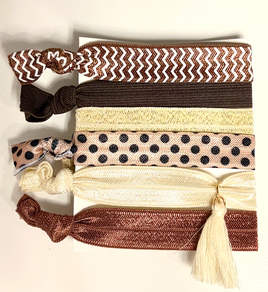 This set of hair ties features 6 different earth tone bobbles. The set includes a glittery gold hair tie, a chevron print, a spot print and 3 plain colours (brown, rust and cream). Perfect for keeping your hair tied up or even worn on your wrist as an accessory.