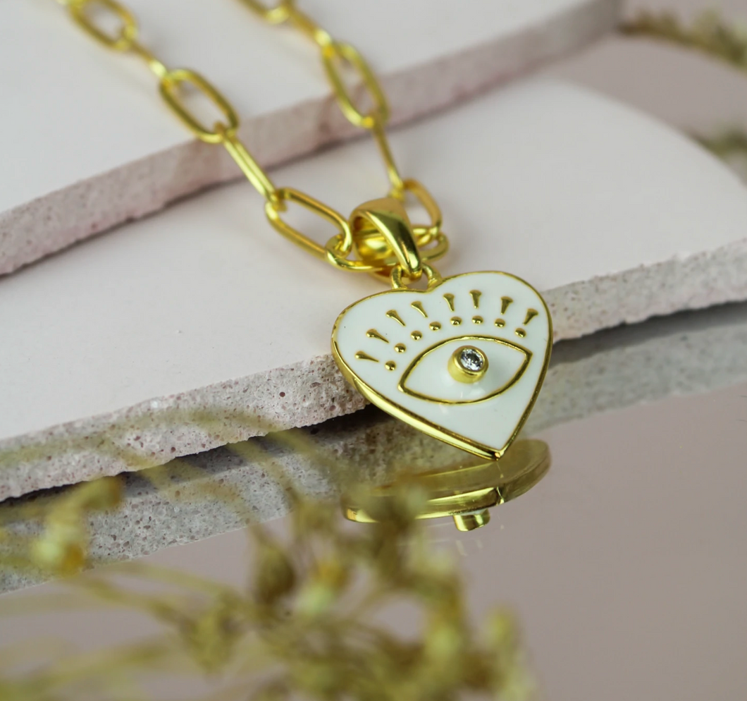 White heart necklace with a gold eye design and a central cubic zirconia crystal..