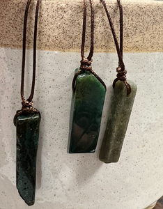 A deep green stone on a brown adjustable cord