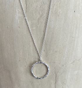 A hammered effect sterling silver circle pendant on a sterling silver chain.