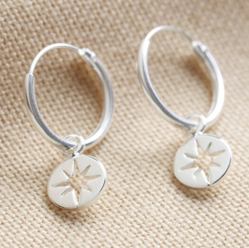 Sterling silver hoop earrings, with a small disc featuring a tiny shooting star. 