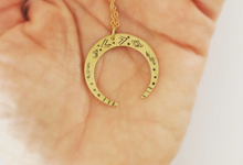 Load image into Gallery viewer, A brass crescent moon pendant necklace with hammered mystic designs hammered into it.