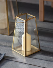 Load image into Gallery viewer, This elegant lantern is made from brass. It features glass sides, and to the top there is a brass handle which can be lifted up or down. The lantern has a flat base so candles can be stood inside, and to the underneath there is a black felt base so it can stand on a table or mantelpiece. 
