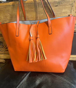 A faux leather orange tote bag with tassels and an inner crossbody bag 