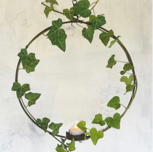 Circular florists ring with a votive at the base. Made in a rust effect hanging on a chain.
