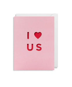 A pink card with I love us in embossed in red 