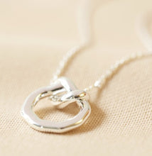 Load image into Gallery viewer, This sterling silver plated ladies necklace features an organic-shaped circle, complete with an infinity knot. The pendant has a delicate chain threaded through the loop which fastens with a lobster clasp for easy securing.