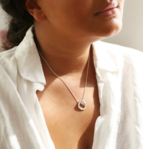 This sterling silver plated ladies necklace features an organic-shaped circle, complete with an infinity knot. The pendant has a delicate chain threaded through the loop which fastens with a lobster clasp for easy securing.