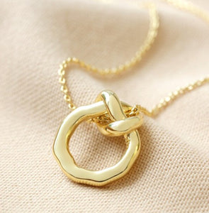 This 14ct gold plated ladies necklace features an organic-shaped circle, complete with an infinity knot. The pendant has a delicate chain threaded through the loop which fastens with a lobster clasp for easy securing.
