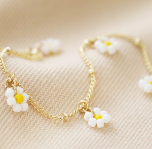 Made from 14ct gold plated brass, it features white and yellow bead daisy charms which dangle from the chain. The chain is a satellite style with a lobster clasp and a 3cm extender chain for adjustable wearing.
