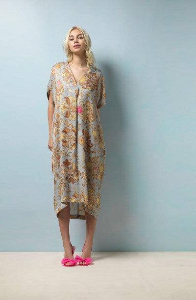 A midi length dress in a beautiful soft and elegant print based on Tudor silk embroidery. The background of the dress is pale grey blue with neutral tones to the print with subtle hints of pink and blue. A midi length, dropped shoulder short sleeve, V neck and pleat to front neck. One size. 