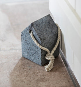 A door stop in the shape of a simple house with a strong hemp rope