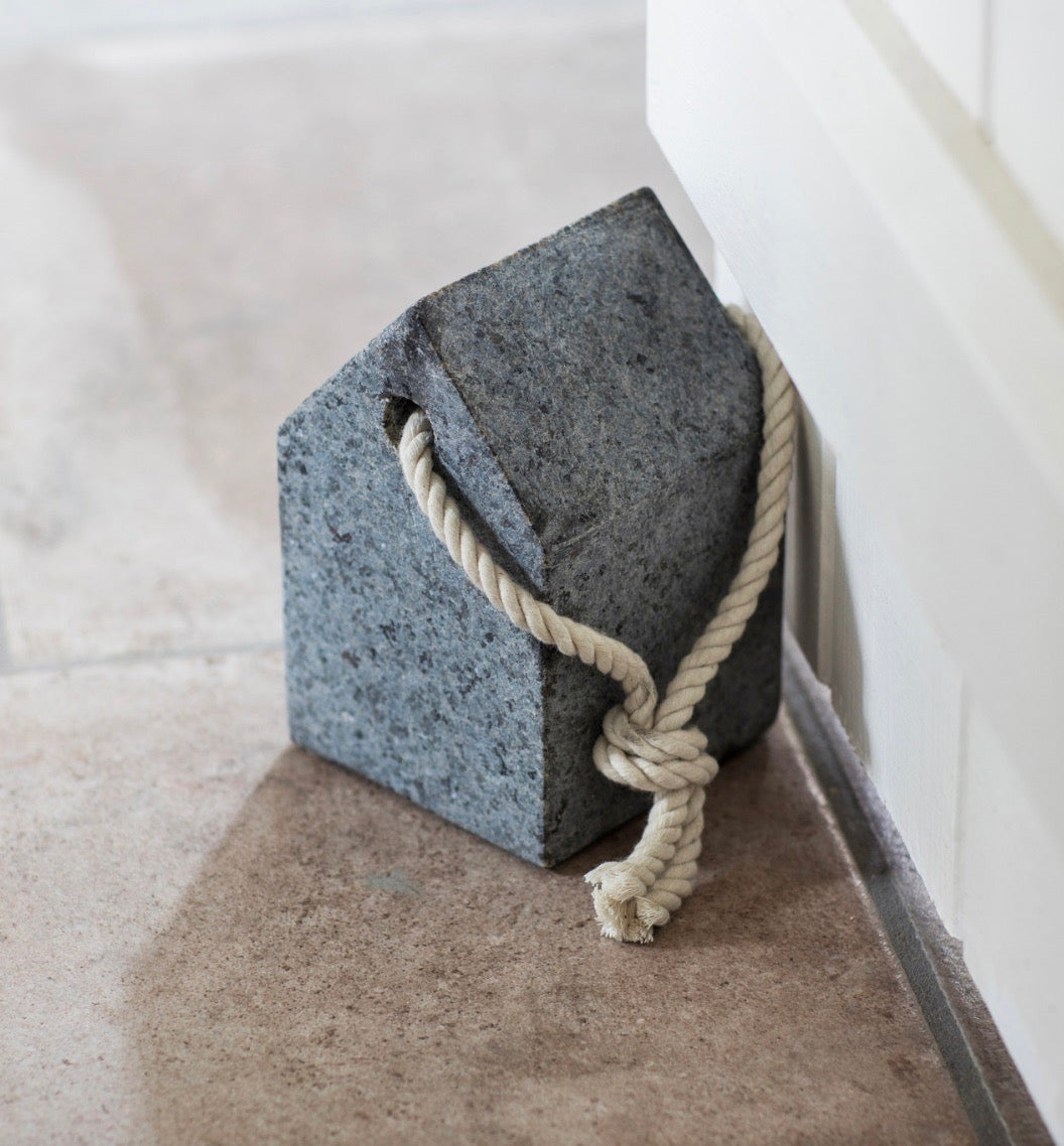 A door stop in the shape of a simple house with a strong hemp rope