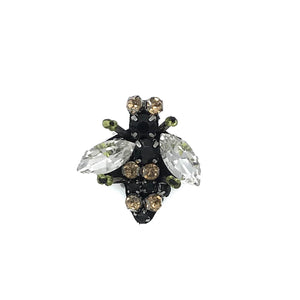 A bee pin with clear jewel wings and a body of black and gold beads