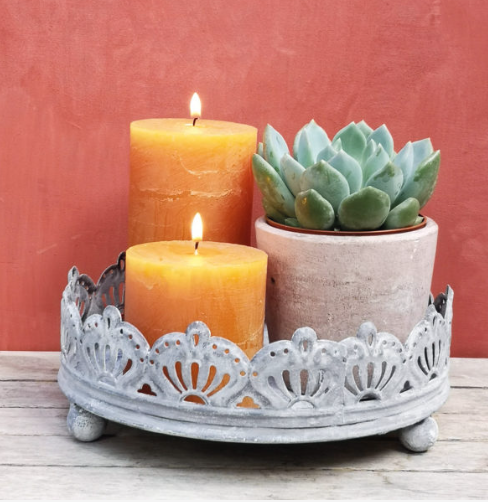 This round metal candle tray is in an antique grey distressed finish. With 3 ball feet to the base and decorative design, it is perfect for standing your pillar candles on, whether that be on your coffee table or dining room table, inside or out. You can also use it to stand your pot plants on. Making it a versatile home accessory. 