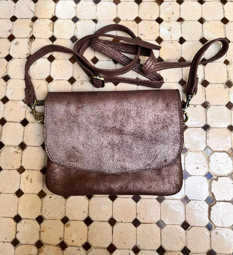 In a rich brown metallic leather, this small ladies handbag is handmade in Morocco.  You can wear it across your body or shoulder with the detachable shoulder strap, or you can attach the wrist strap instead to turn it into a clutch bag. The main compartment is zipped to keep your belongings safe.