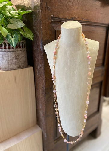 Long pink beaded and gold metal necklace. Pink beads of various shades, shapes and sizes. Clasp fastening to the back with adjustable length. Nickel free. 