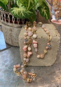 Long pink beaded and gold metal necklace. Pink beads of various shades, shapes and sizes. Clasp fastening to the back with adjustable length. Nickel free.