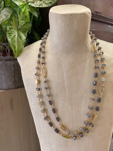A short ladies necklace with beads in grey and gold in various shapes and shades. A double layered style fastened by a clasp at the back which is adjustable.